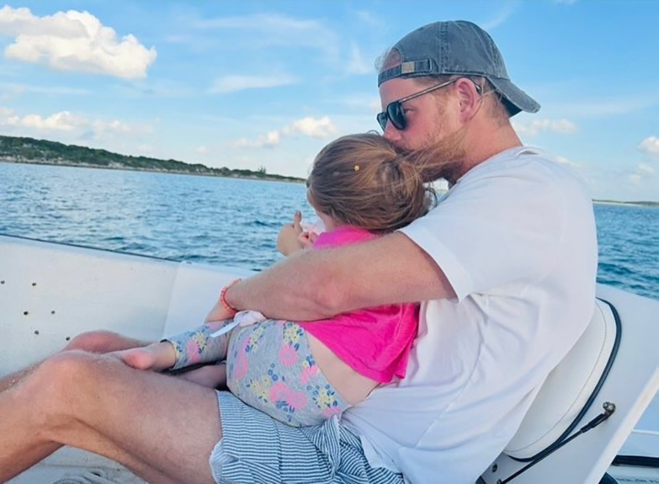 Prince Harry kissing his daughter Lilibet on a boat.