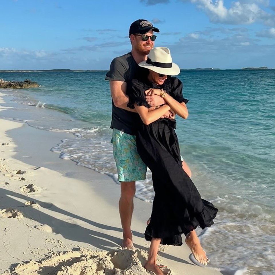 Prince Harry and Meghan Markle embracing on a beach.