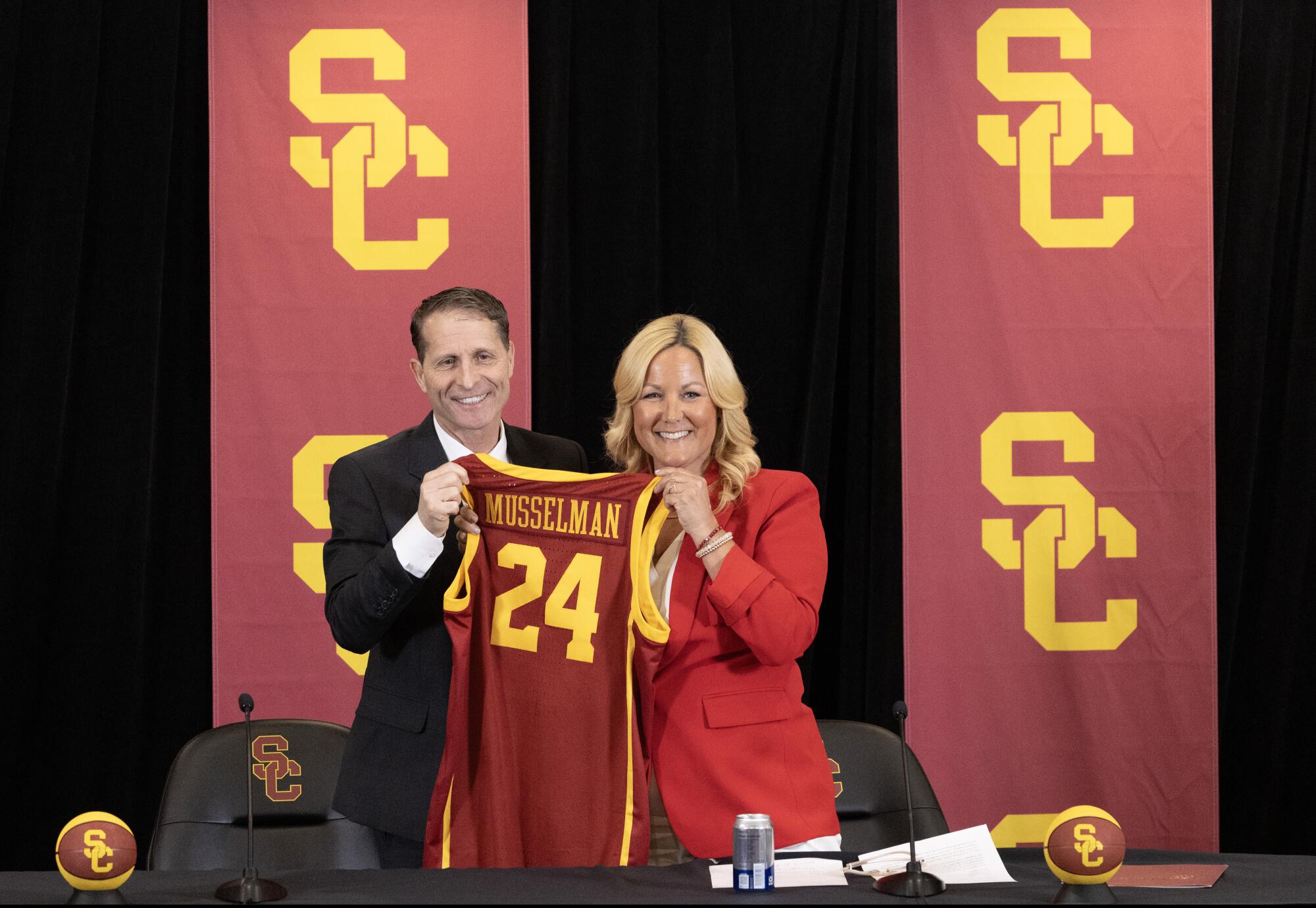 Eric Musselman and USC athletic director Jennifer Cohen hold up his jersey during a news conference