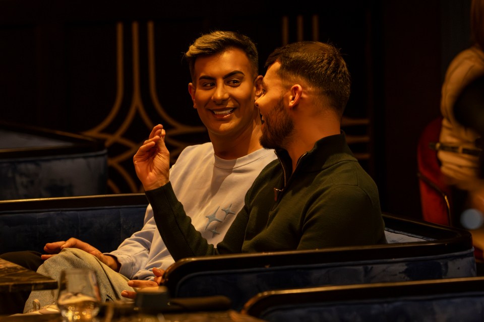 Two men sitting and talking in a restaurant booth.