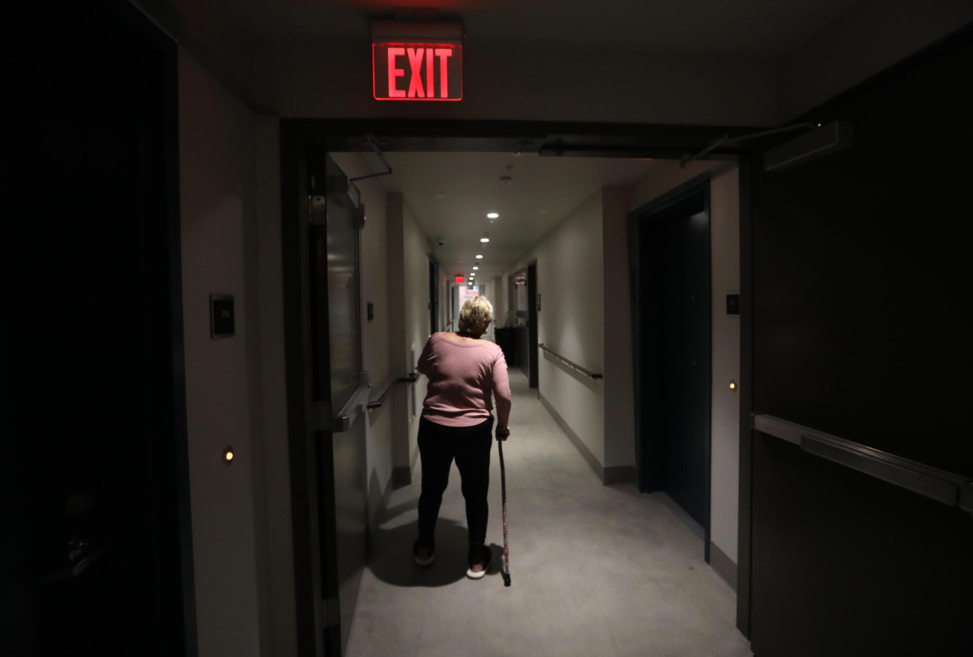 A woman walks through the hallway of an apartment building.