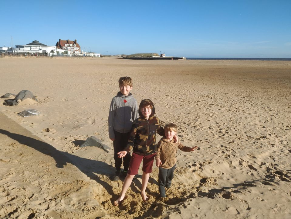 Three boys on a sandy beach.