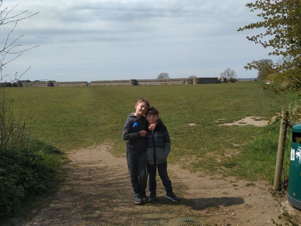 Two boys standing in front of a stone wall.