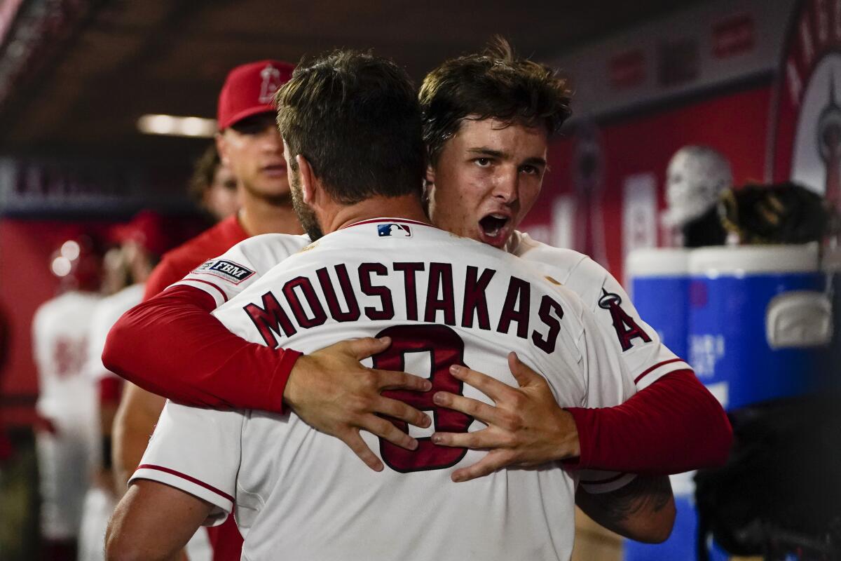 Los Angeles Angels' Mike Moustakas (8) hugs teammate Mickey Moniak after a three-run home run.