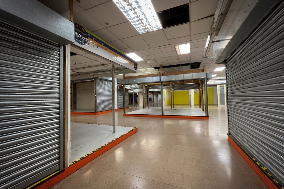 Empty stalls in Victoria Centre Market with closed security shutters.