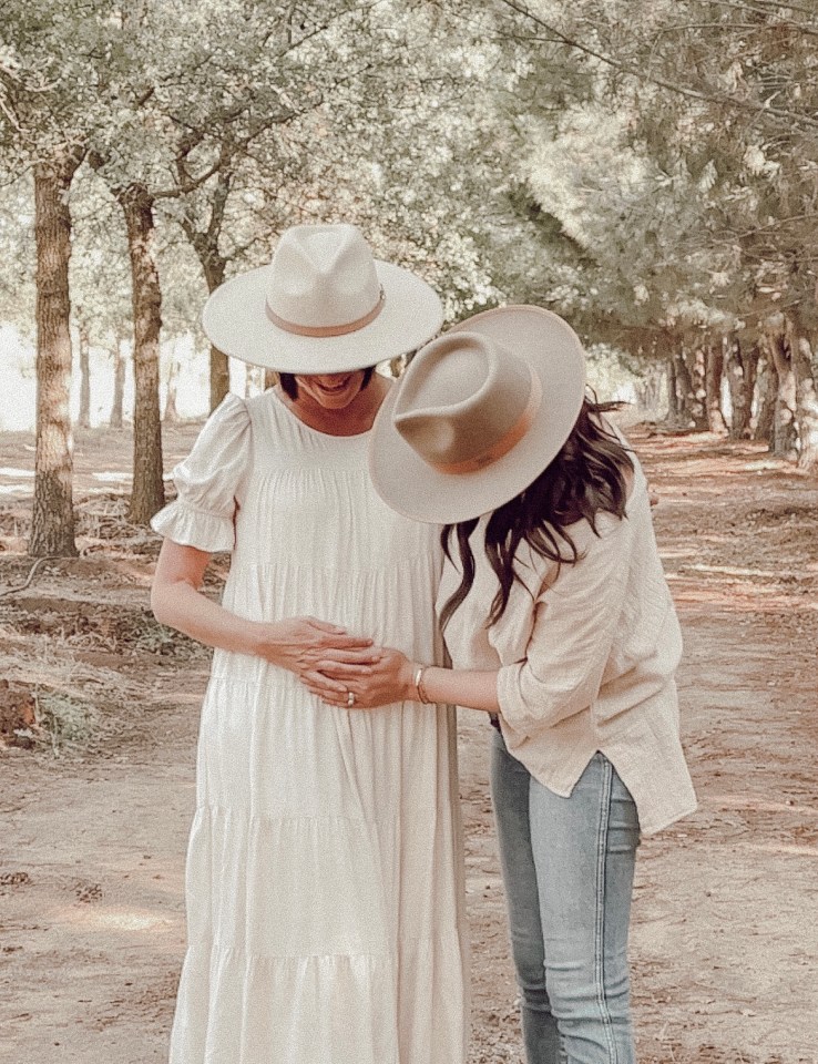 A pregnant woman and another woman holding her belly.