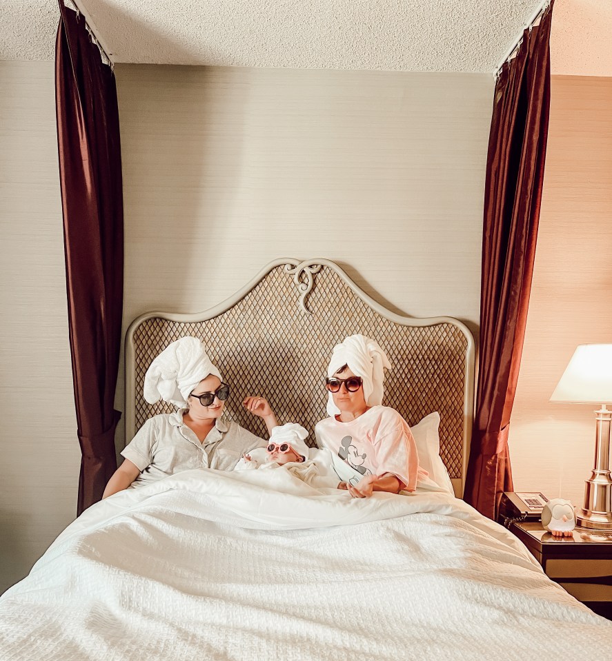 Grandmother, mother, and baby granddaughter in bed wearing towels and sunglasses.