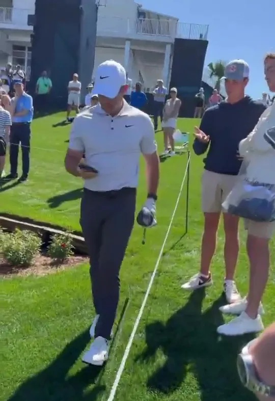 Rory McIlroy takes a fan's phone and walks away.