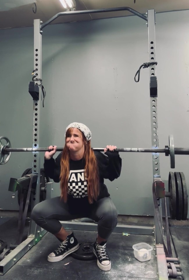 Woman squatting with barbell in home gym.