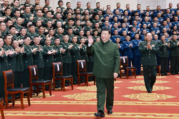 Xi Jinping walking among applauding military personnel.