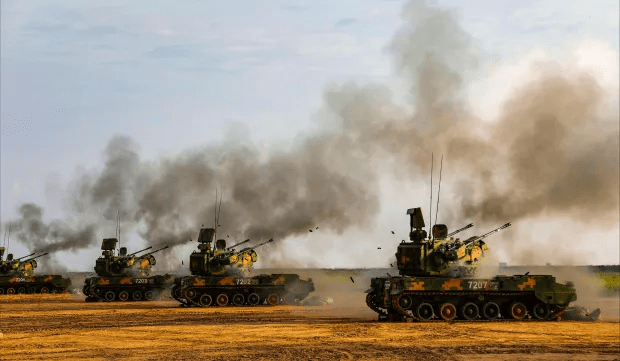 Military vehicles firing in a field.