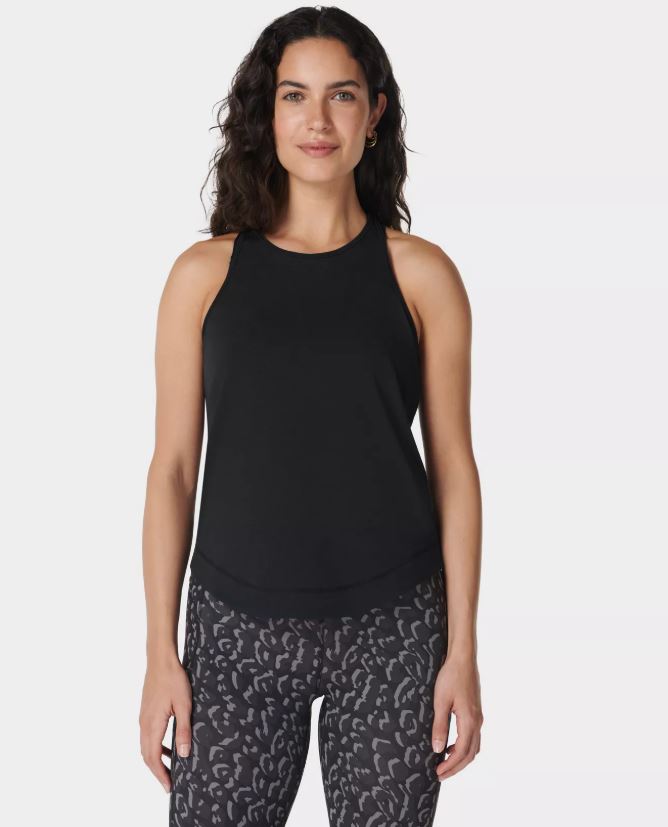 Woman wearing a black tank top and patterned leggings.