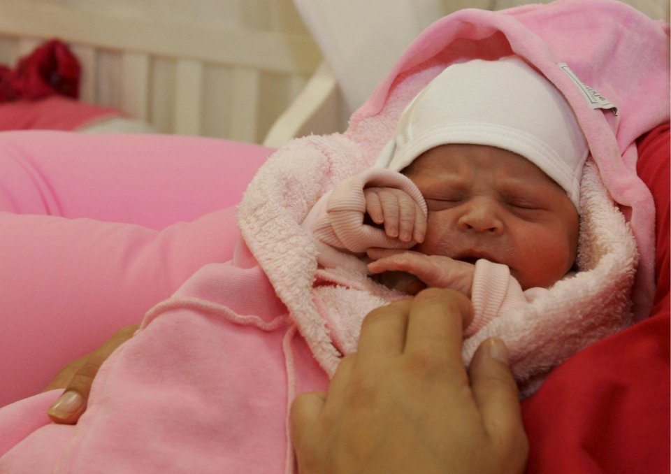 Newborn baby girl sleeping in pink clothing.