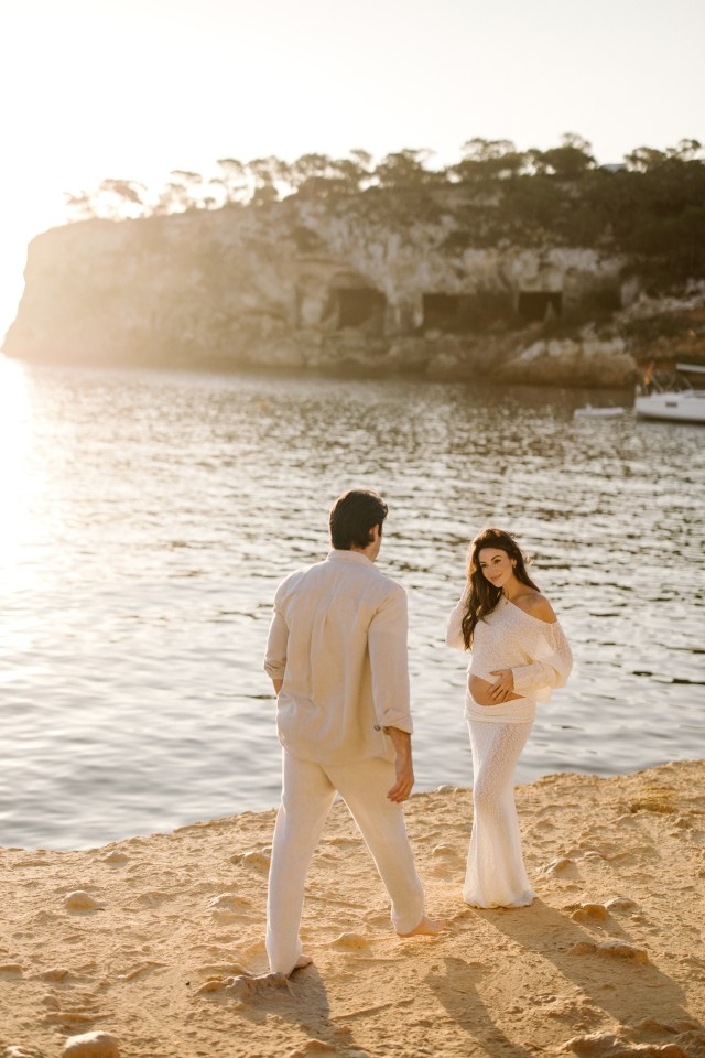 Pregnant woman and man on beach.