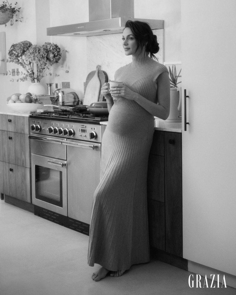 Black and white photo of Michelle Keegan in her kitchen, holding a mug.