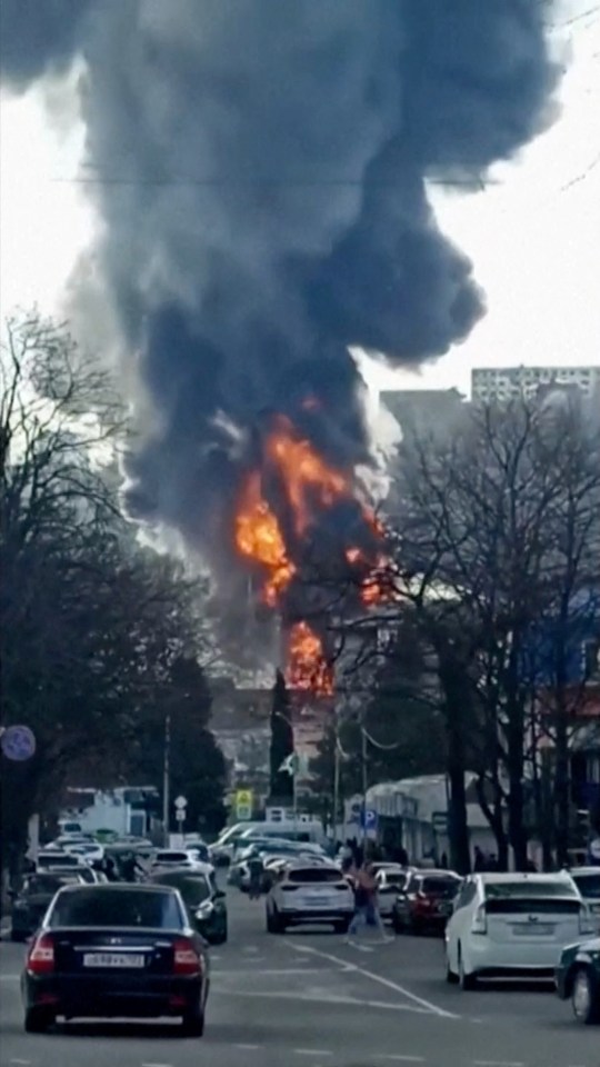 Large fire and smoke billowing near a road with vehicles.