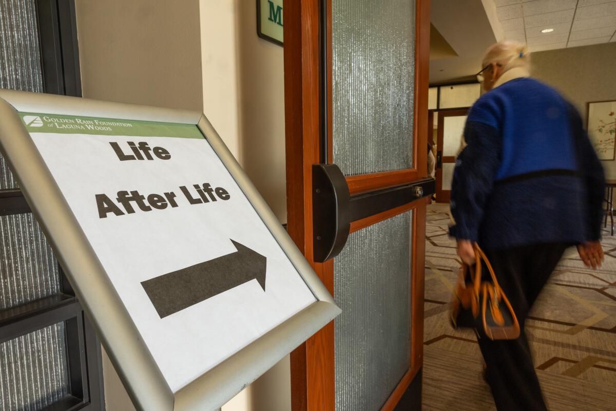 A woman walks past a sign pointing in the direction of the Life after Life club at a retirement home in Laguna Woods.