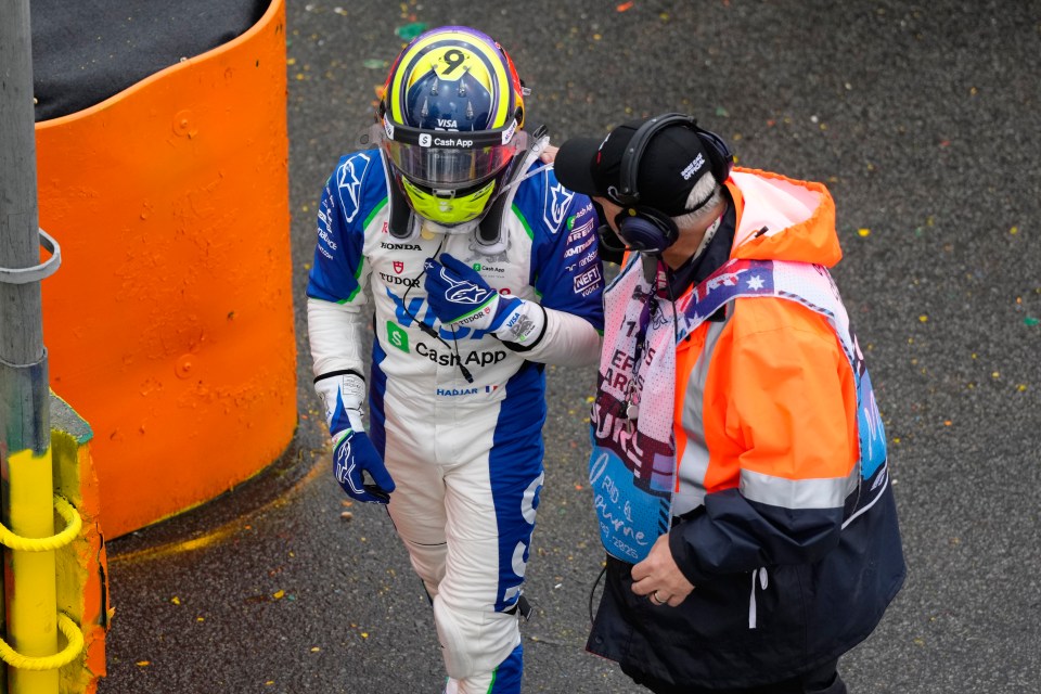 Formula One driver Isack Hadjar being assisted by a track marshal.