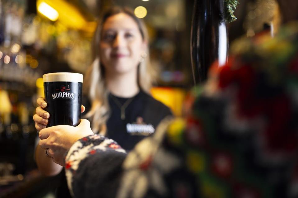 A pint of Murphy's Stout being handed to someone.