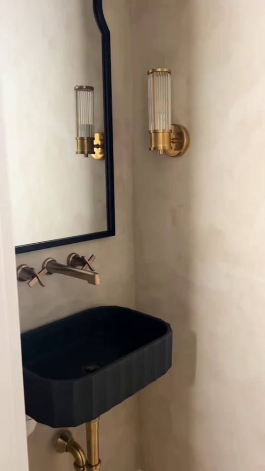 Small black sink and brass fixtures in a powder room.