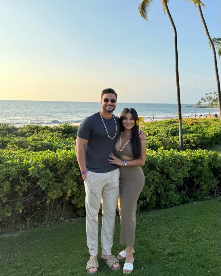 Couple posing on beach with ocean in background.