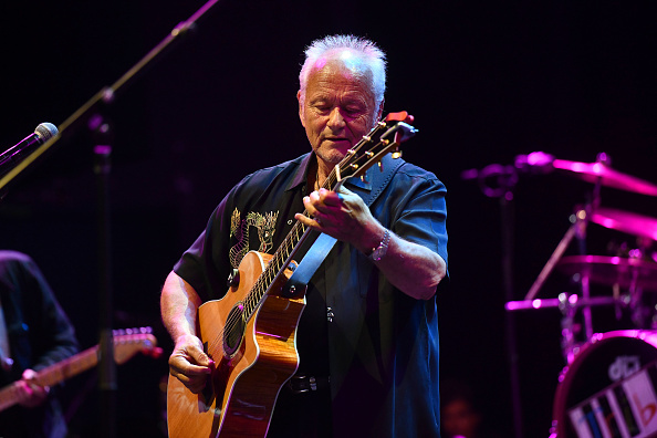 Jesse Colin Young playing acoustic guitar onstage.