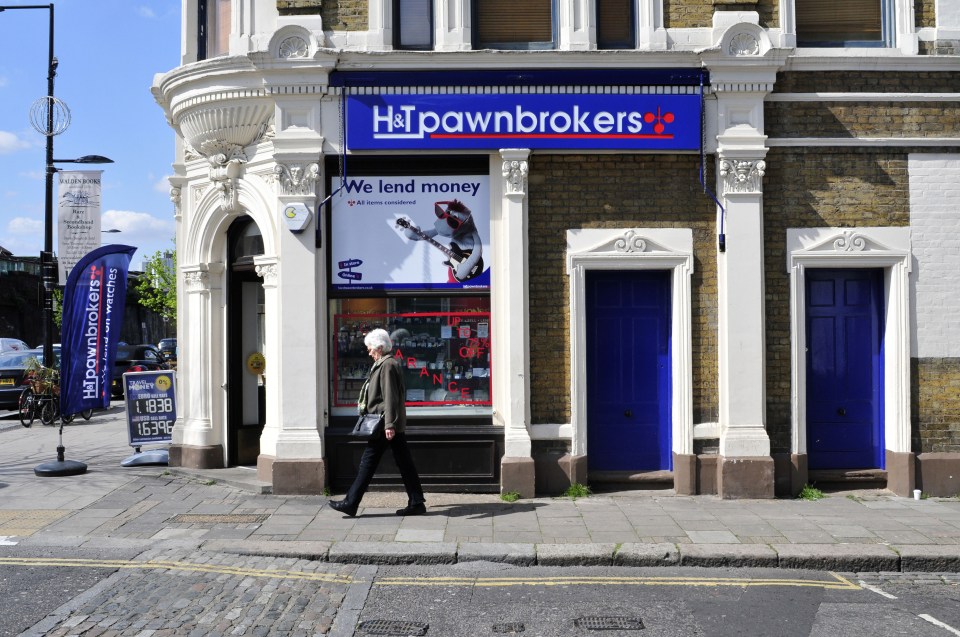 Woman walking past an H&T Pawnbrokers shop in London.