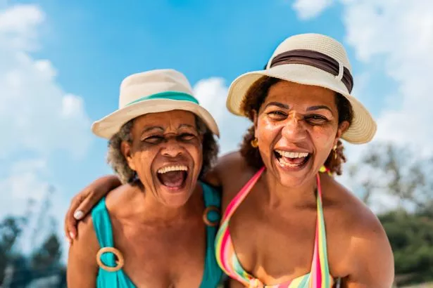 Two female holidaymakers laughing in sunhats