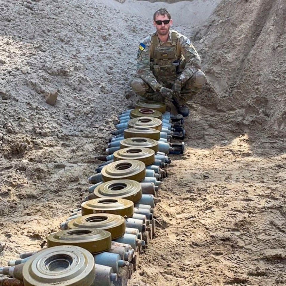 A bomb disposal expert sits amidst a row of Russian munitions.