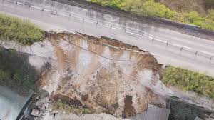 Aerial view of a large landslip next to a highway.