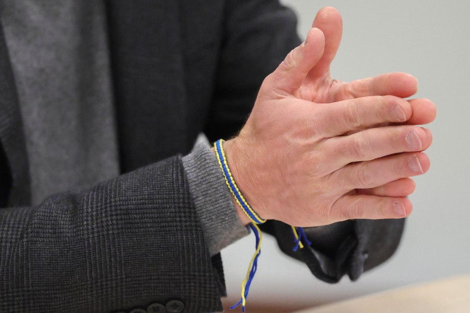 Close-up of a person's hands clasped together, wearing a blue and yellow bracelet.