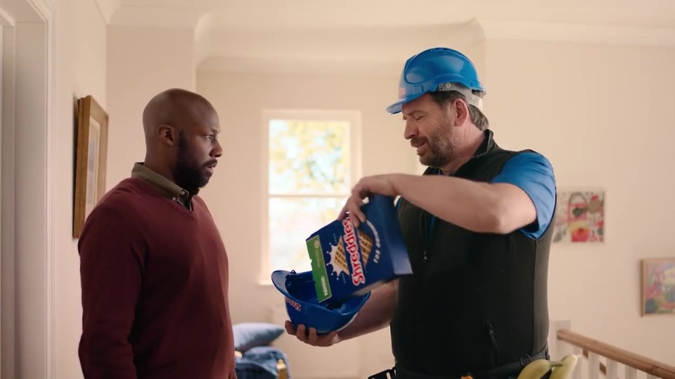 Nick Knowles placing a box of Shreddies into a hard hat.