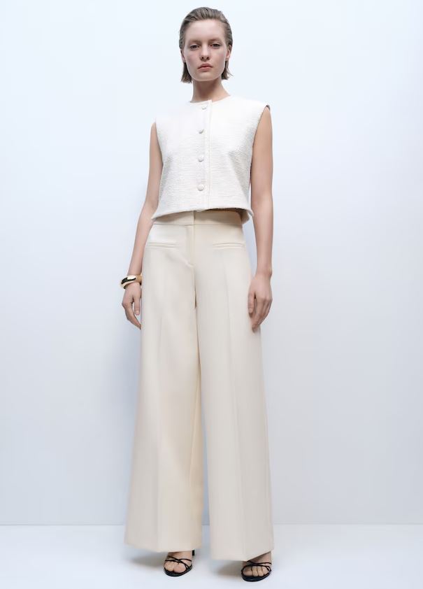 Model wearing cream-colored wide-leg trousers and a cream textured sleeveless top.