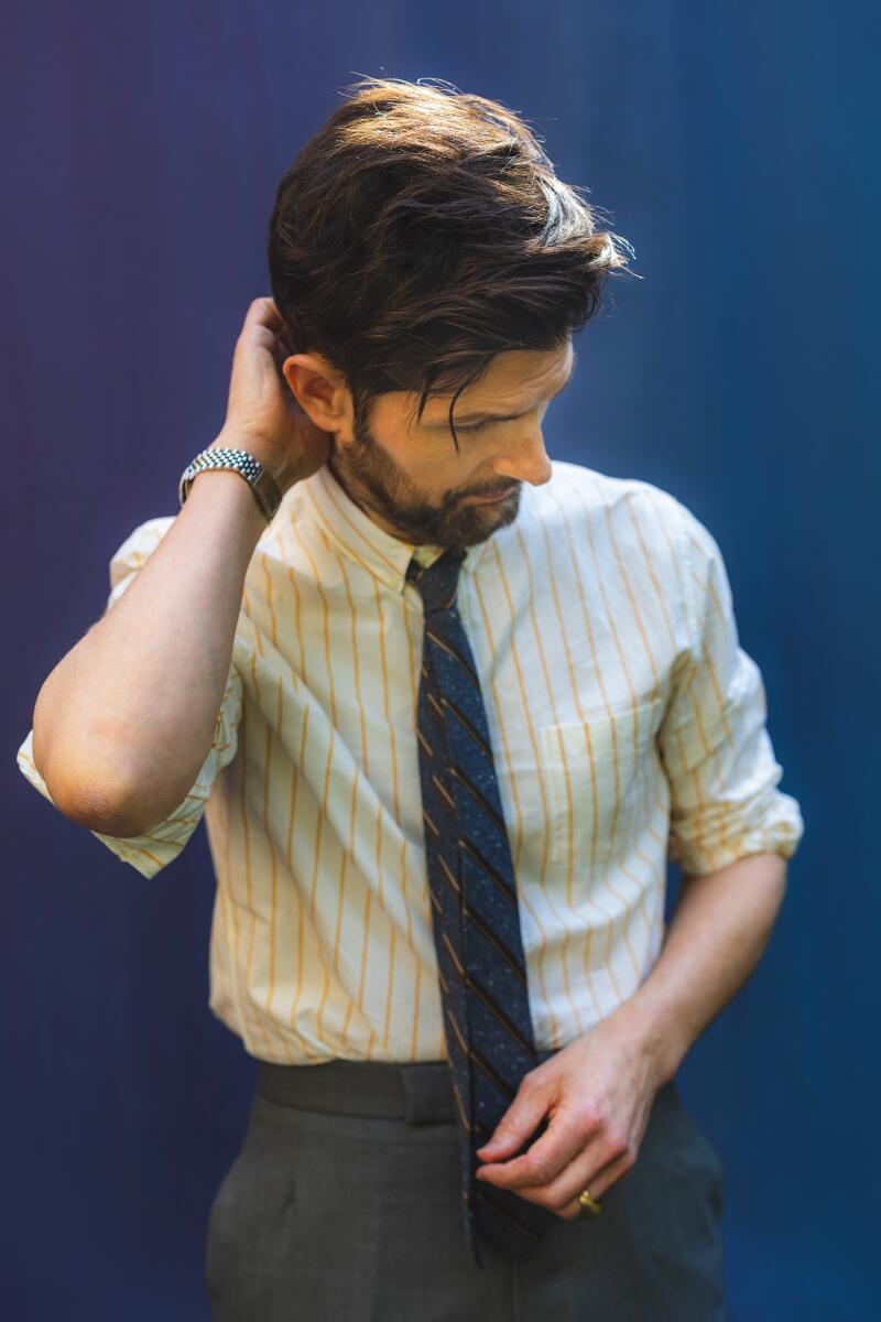 A man in striped shirt and blue tie looking downward.