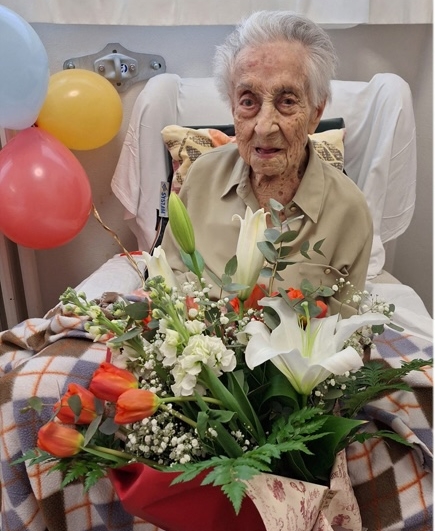 Maria Branyas Morera, the world's oldest person, holding a bouquet of flowers.