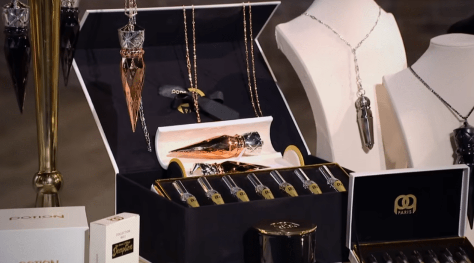 Several perfume sets displayed on stands, including rose gold and silver pendants.