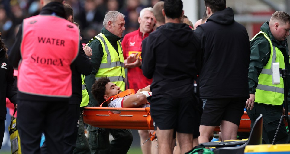 Injured rugby player being carried off the field on a stretcher.