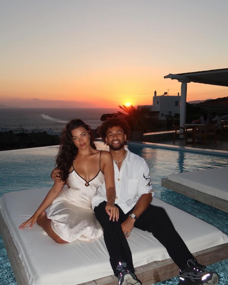 Couple sitting by a pool at sunset.