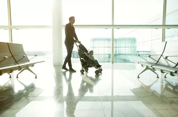 Father pushing baby in pram at the airport