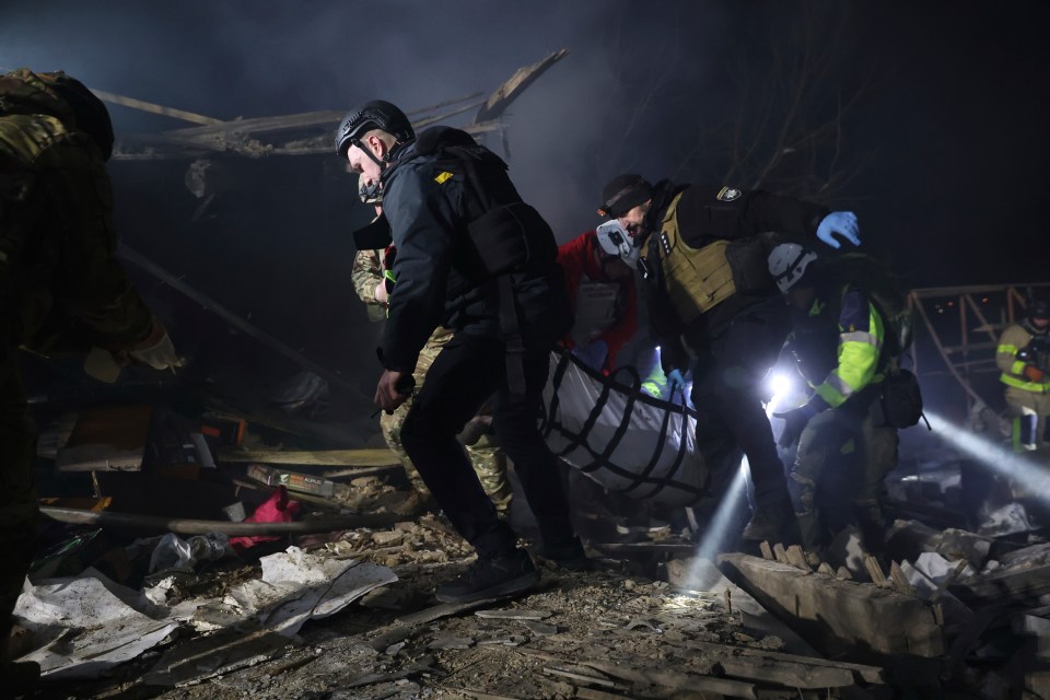 Police officers carry a body from a destroyed building.