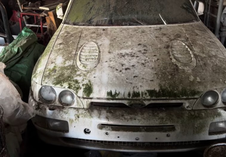 A neglected Ford Escort Cosworth in a garage.