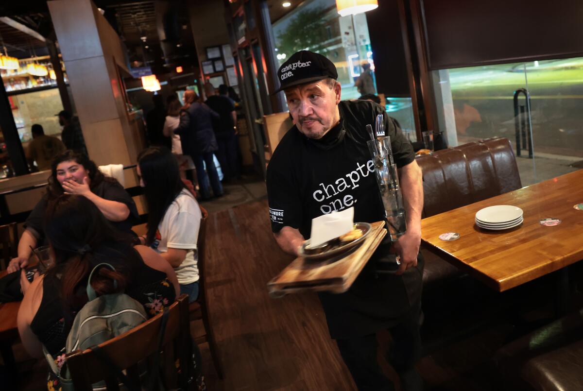 Alfonso Lira carries plates and glasses at a restaurant