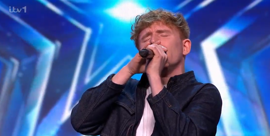 Screenshot of a young man singing into a microphone.