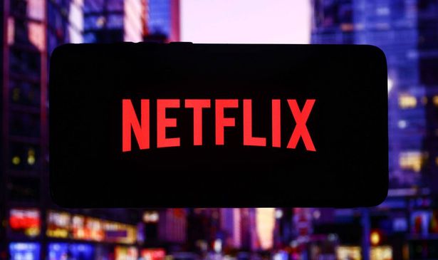 The Netflix logo on a screen with a cityscape in the backdrop