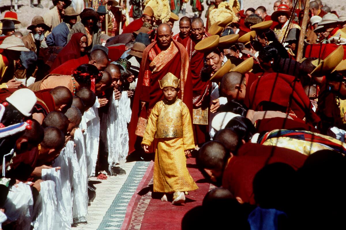 A young emperor in yellow is surrounded by subjects and attendees.