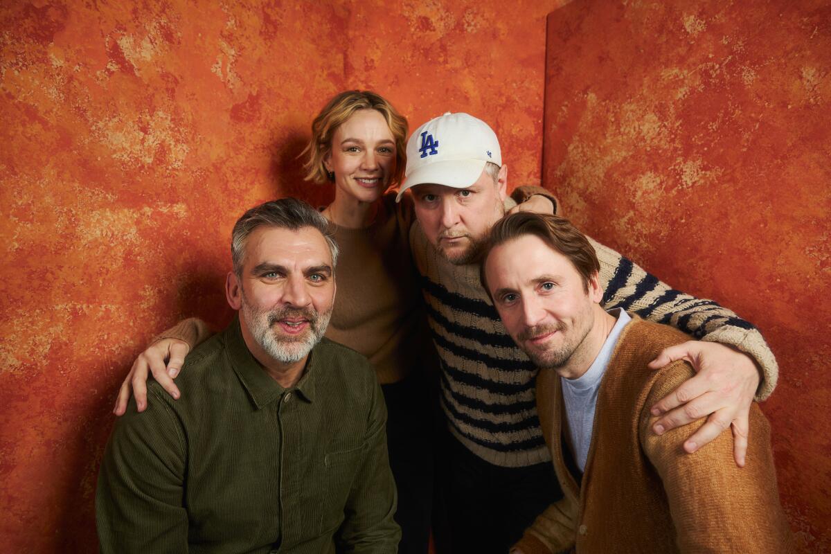 Three men and a woman pose in a group for the camera.