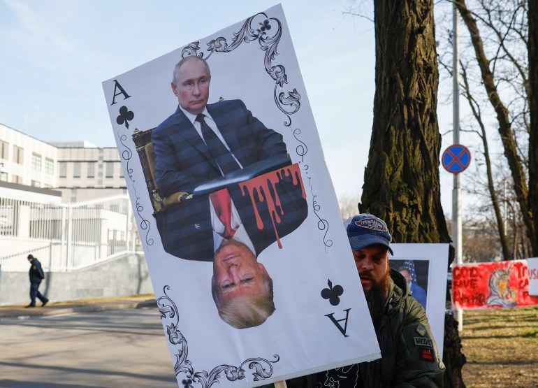 A protester in Kyiv holds up a sign with Putin and Trump as two halves of a playing card.