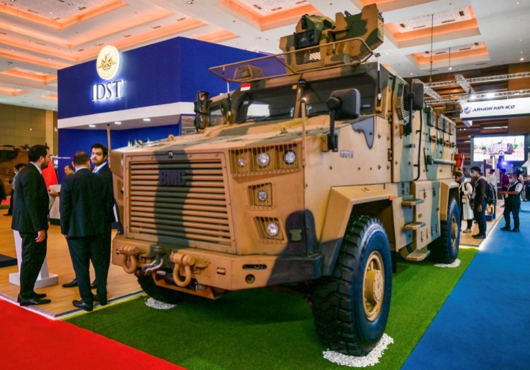 Camoflauge-painted armoured vehicle in an arms expo setting