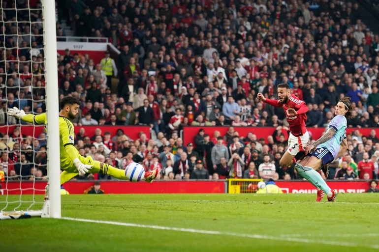 Arsenal's goalkeeper David Raya, left, makes a save during the English Premier League soccer match between Manchester United and Arsenal at Old Trafford stadium in Manchester, England, Sunday, March 9, 2025. (AP Photo/Dave Thompson)