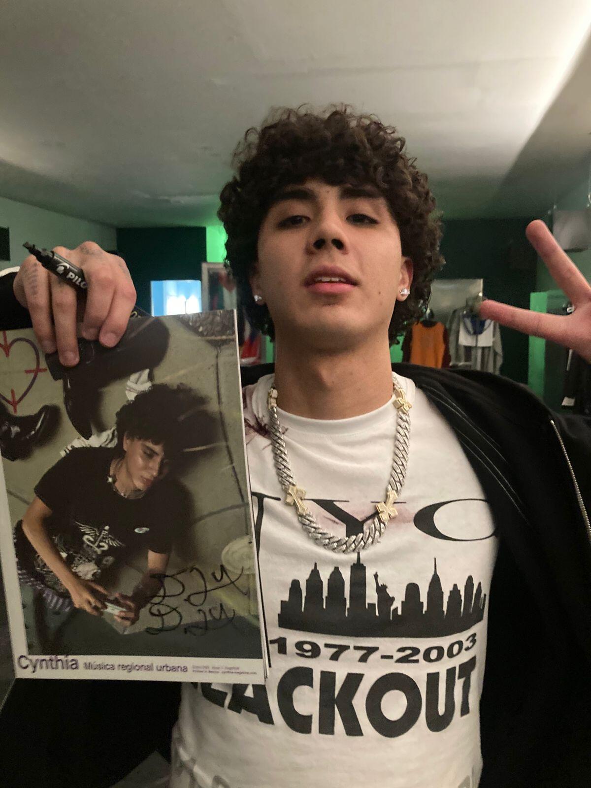 Musician DannyLux holds a copy of the first issue of Cynthia magazine and flashes a peace sign.